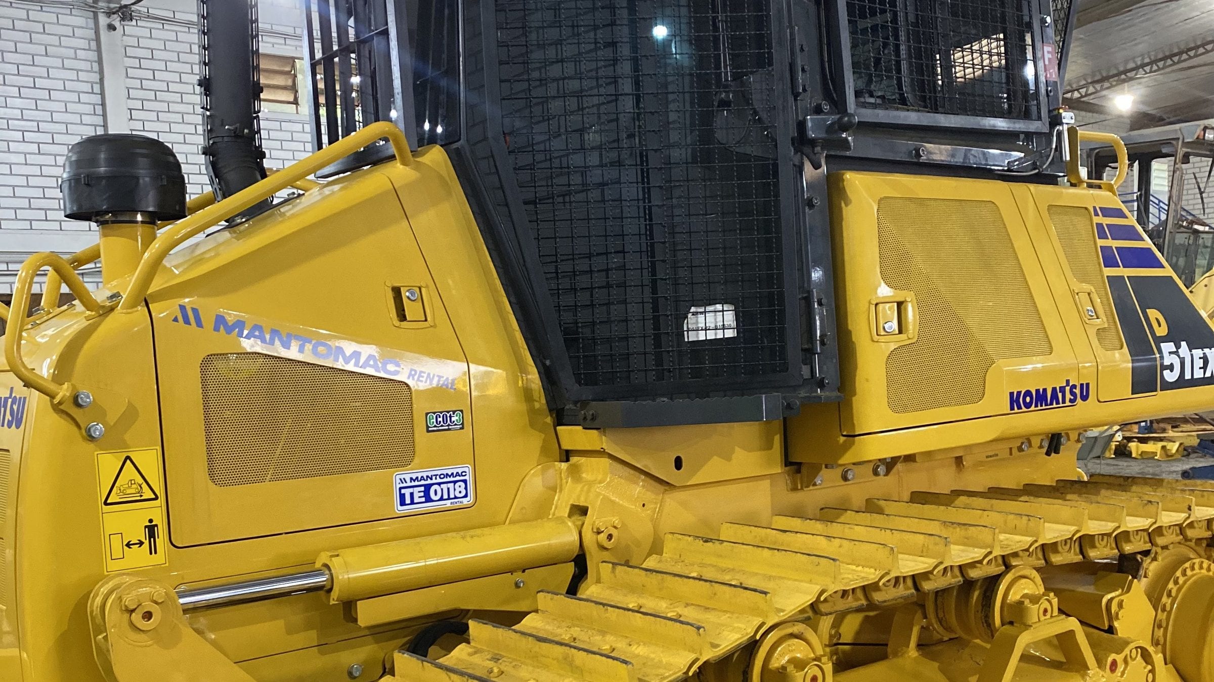 Trator de esteira amarelo em manutenção no pátio, visto de perto